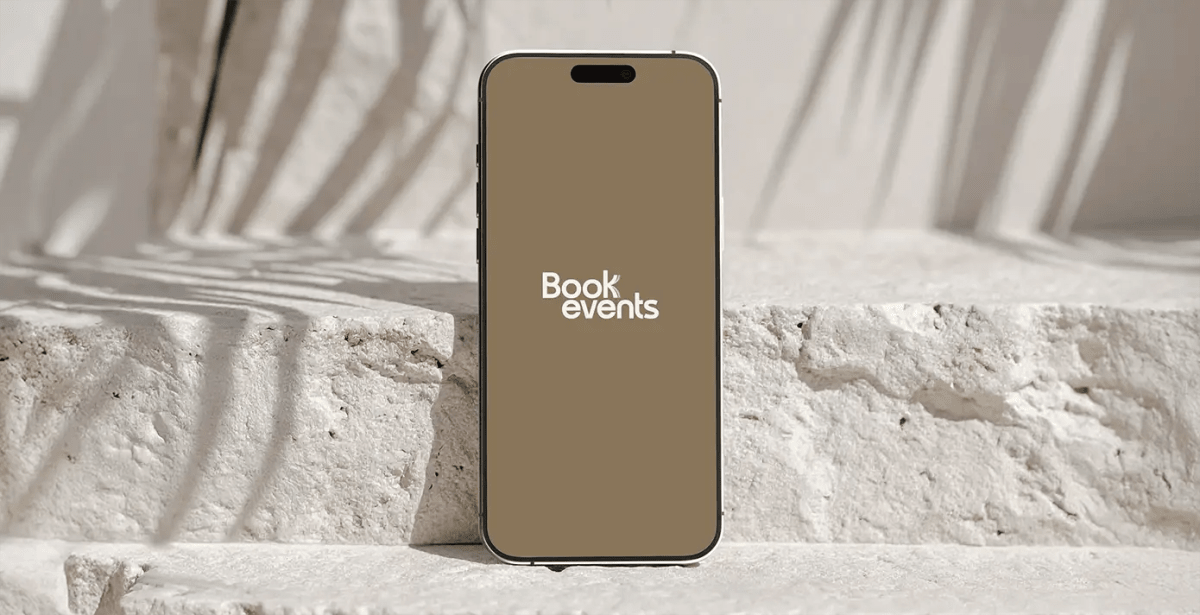 Mockup de móvil con el logo de Bookevents sobre fondo de piedra clara, de Patricia Serrano, alumna de UX/UI/Web en TRAZOS