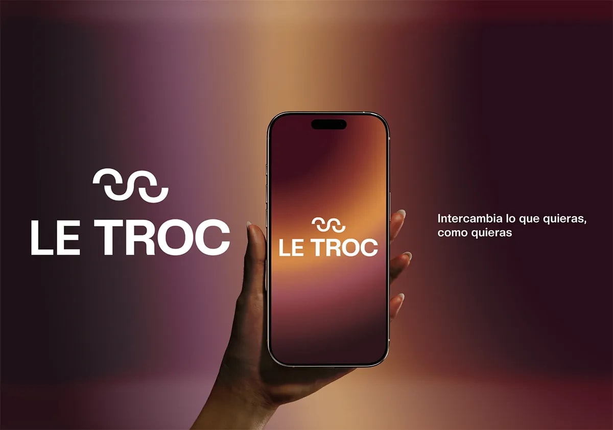 Mockup del logo de la app LE TROC en una mano sosteniendo un móvil sobre fondo degradado cálido, de Rita García, alumna de UX/UI/Web en TRAZOS