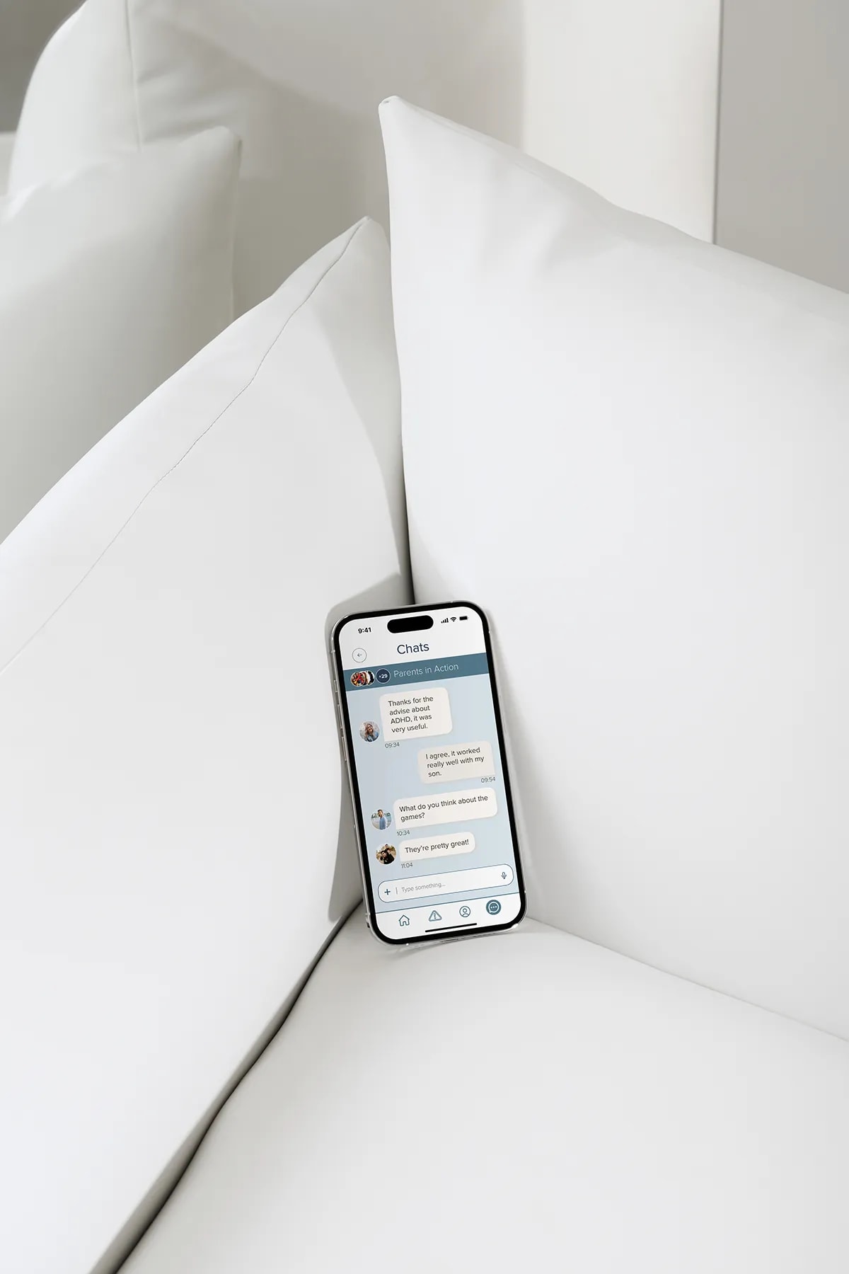 Pantalla de chat de la comunidad de padres de la app Neuro Kids en un móvil sobre cojines blancos, de Diana Barrero, alumna de UX/UI/Web en TRAZOS
