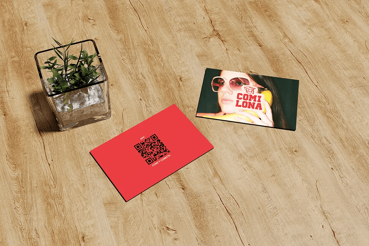 Mockup de tarjetas de visita rojas con la marca COMILONA sobre una mesa de madera, de Sofía Villalta, alumna de UX/UI/Web en TRAZOS