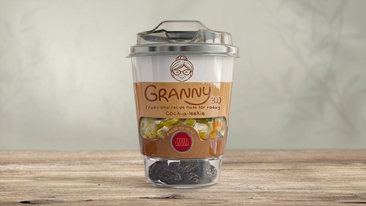Bodegón del vaso de sopa Granny 3.0 sobre una mesa de madera, con el caldo visible tras la ventana del envase, de Katherine Valencia, alumna de Diseño Gráfico y Motion Graphics en TRAZOS