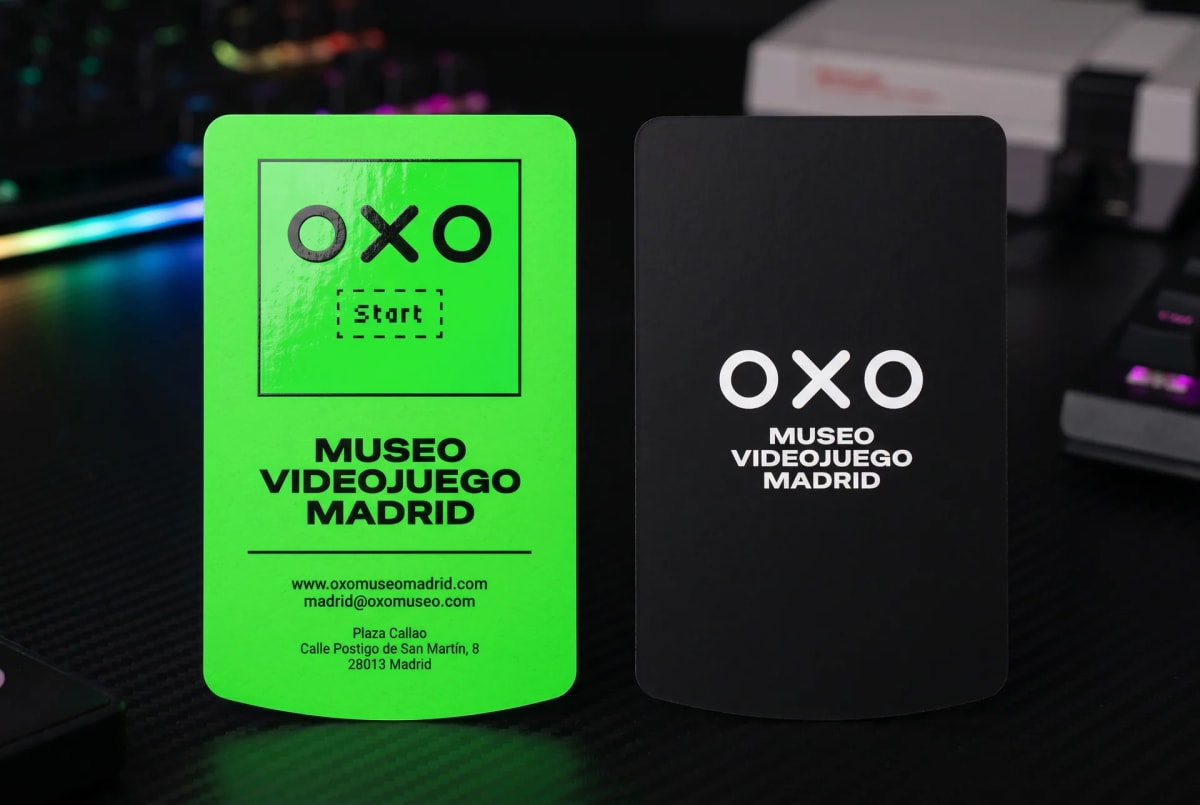 Tarjetas de visita del museo OXO en verde flúor y negro sobre una mesa de setup gamer, de Sandra Marugan, alumna de Diseño Gráfico y Motion Graphics en TRAZOS