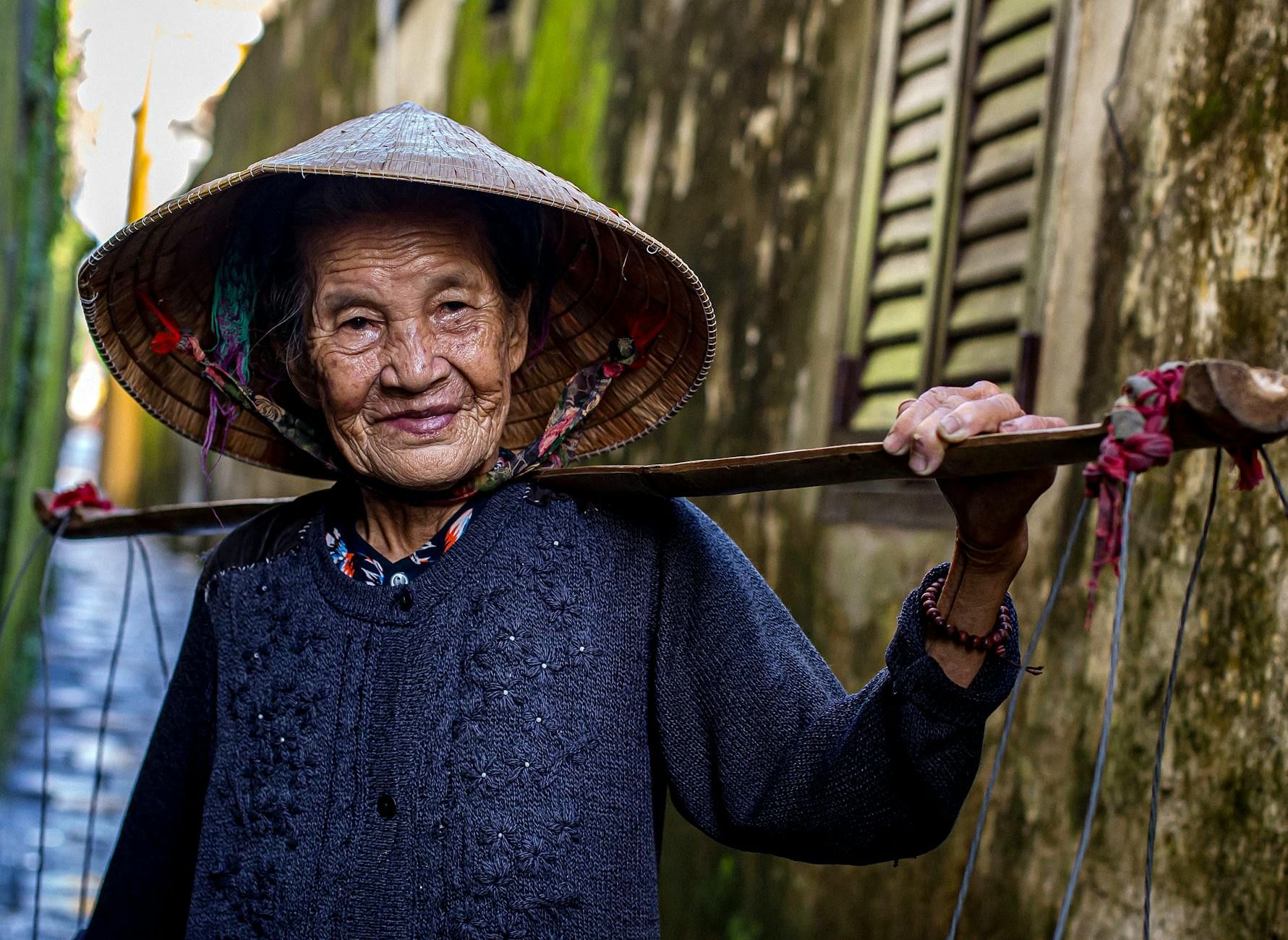 Portrait of elderly woman wearing a conical hat in the streets of Hoi An, Vietnam.