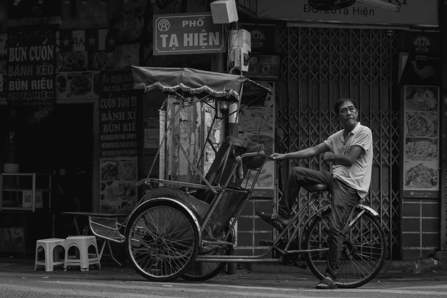 Captivating black and white photo of a cyclo rider on Tạ Hiện Street, Hanoi.