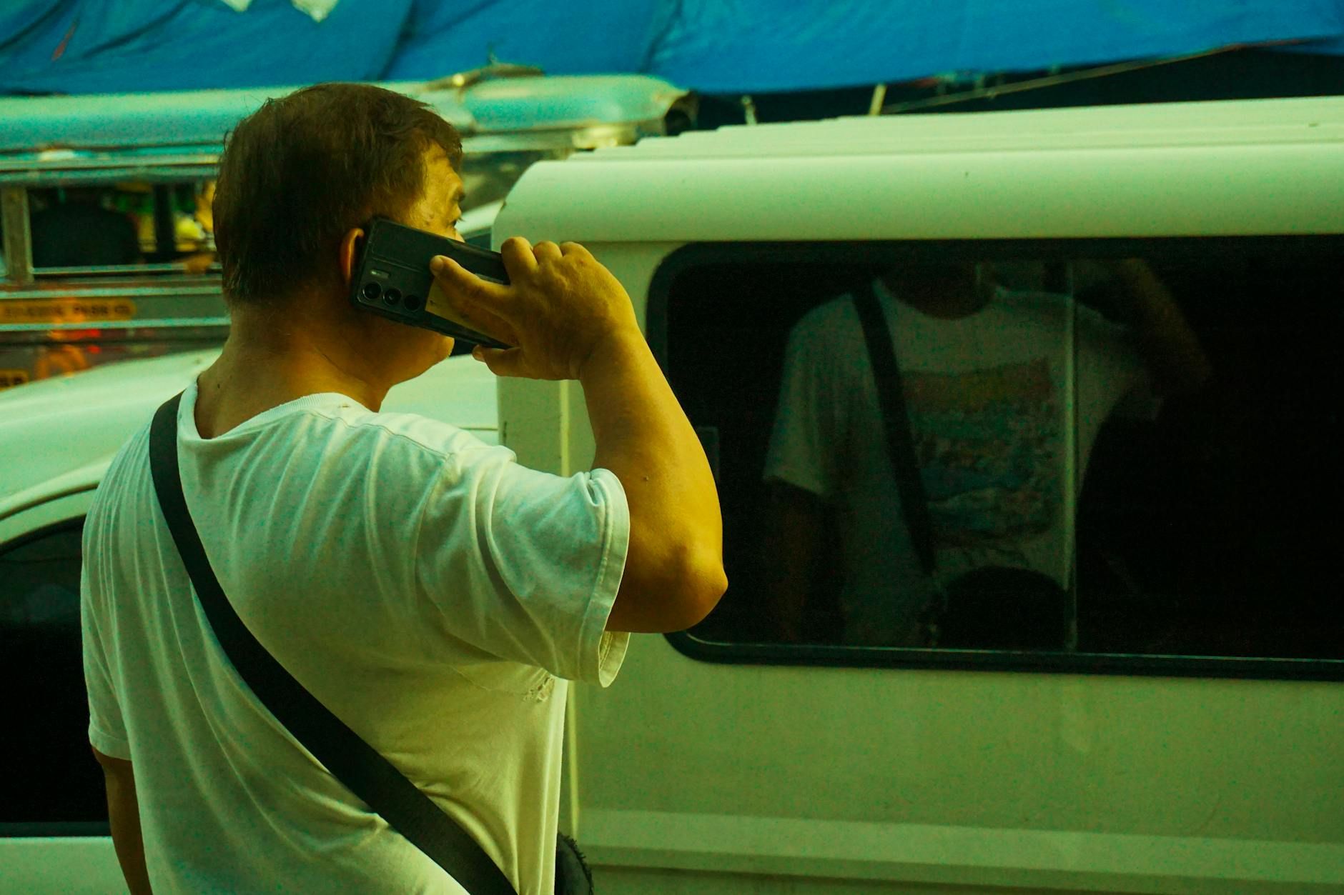 An urban street scene with a man using his mobile phone, captured in a busy city environment.
