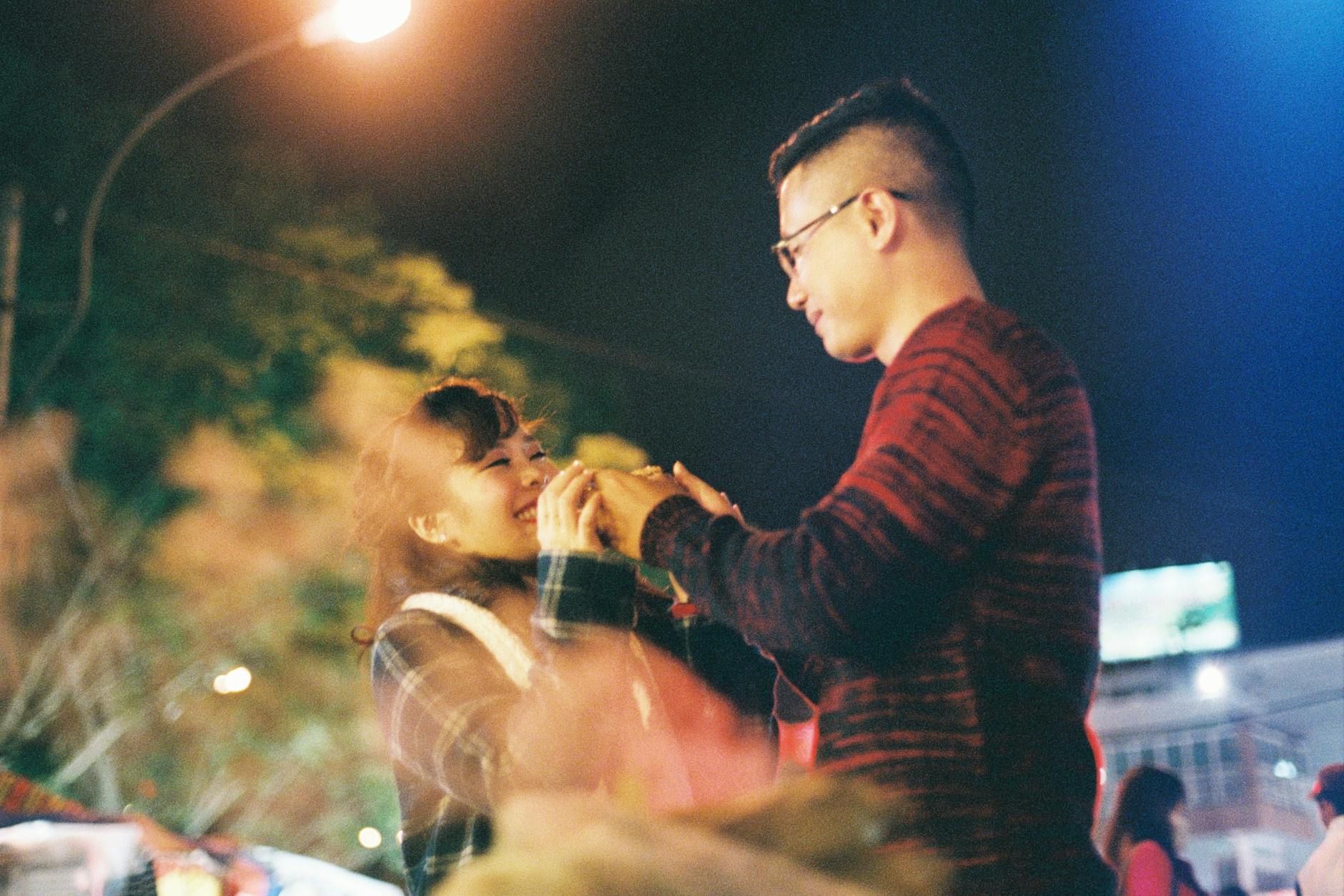 Couple sharing a joyful moment at a vibrant night festival in Da Lat, Vietnam.