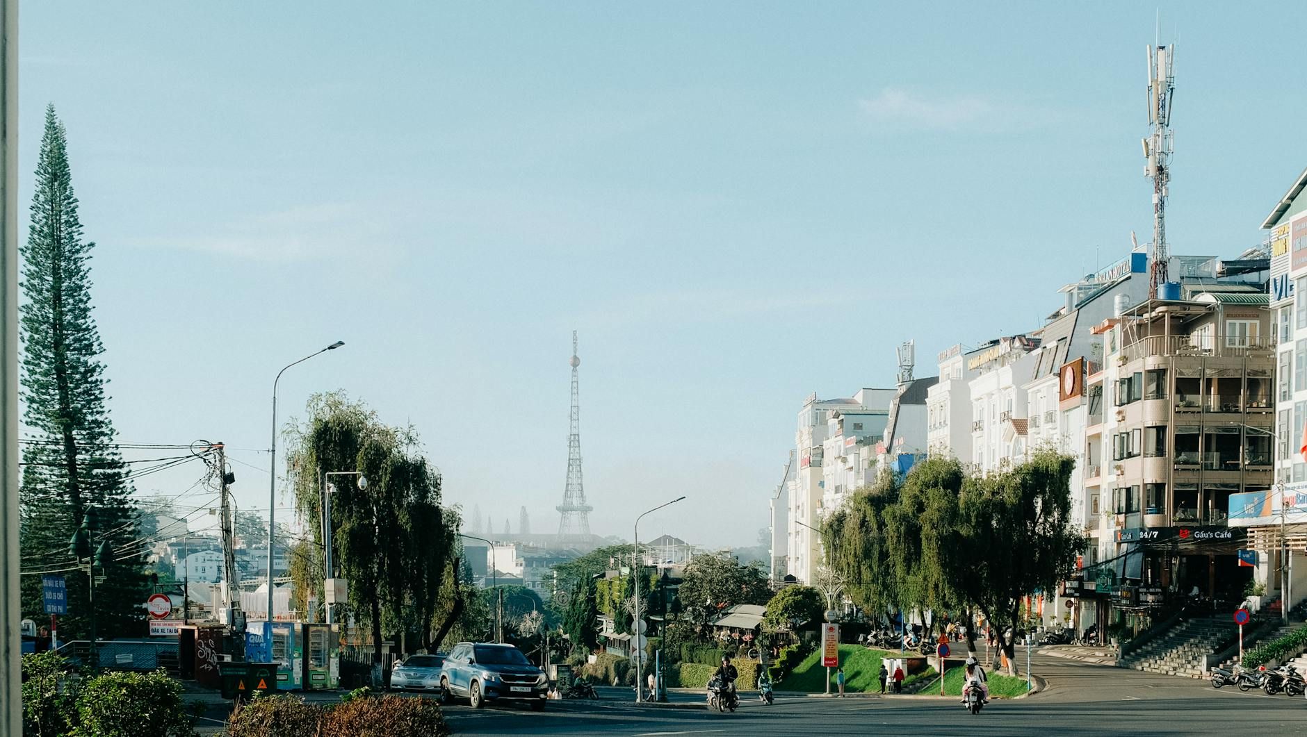 Vibrant street view of Dalat, Vietnam with traffic and landmark tower under clear blue skies.
