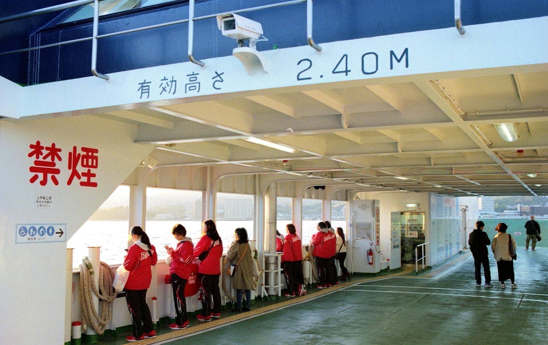 Travelers enjoy scenic views aboard a ferry in Hiroshima, Japan during sunset.