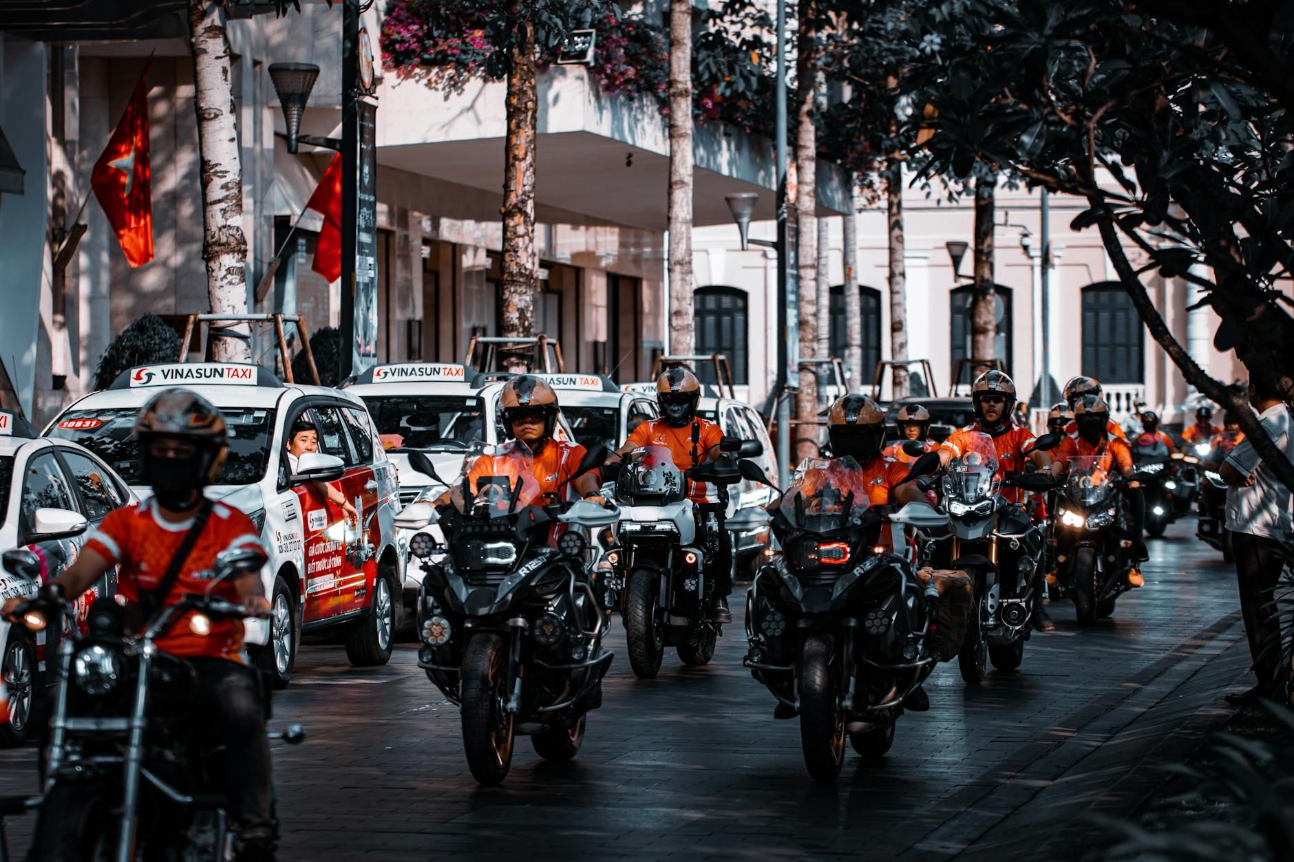 Motorcyclists and taxis in a vibrant city street, showcasing urban traffic.