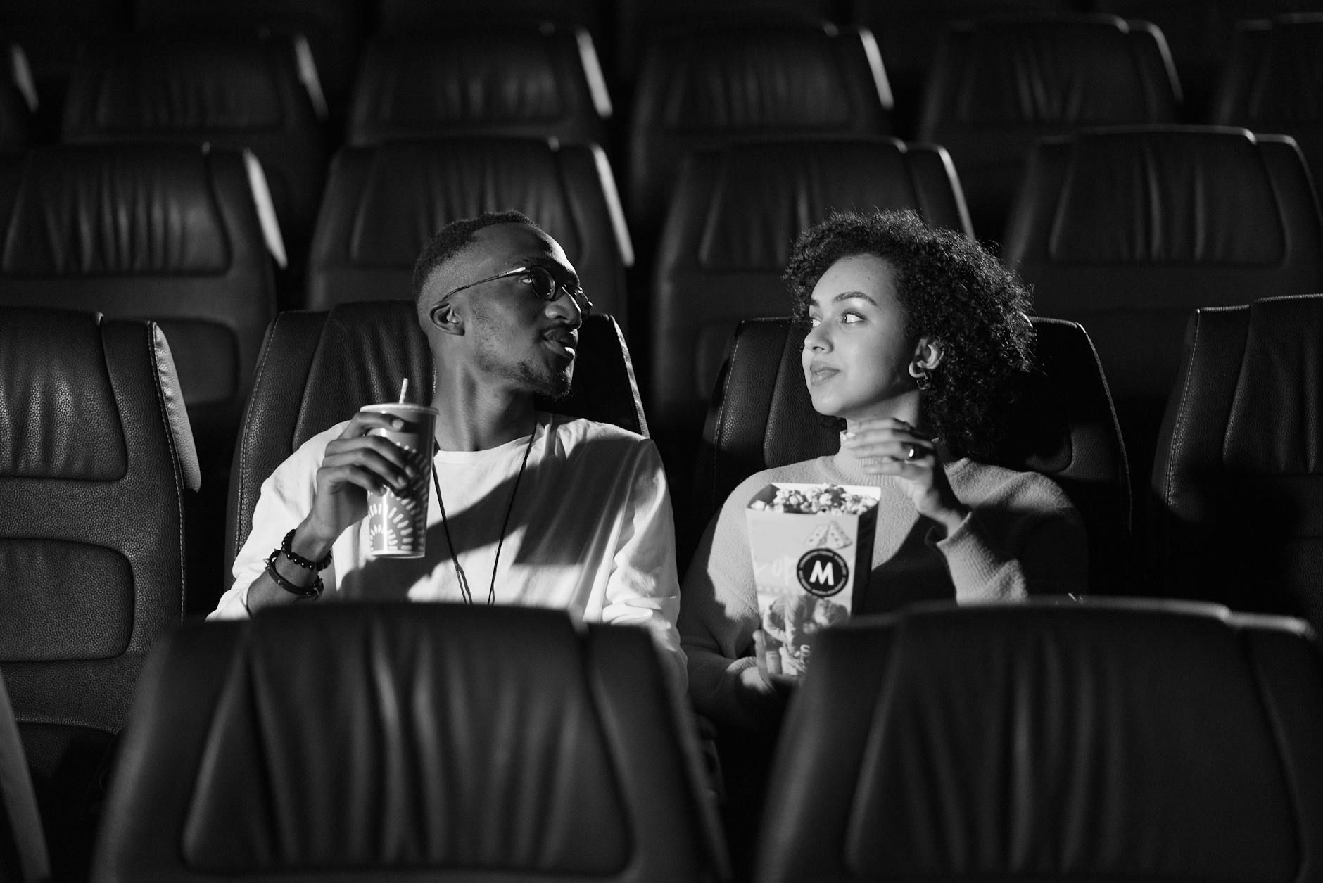 A couple enjoying snacks while watching a movie in an empty theater.