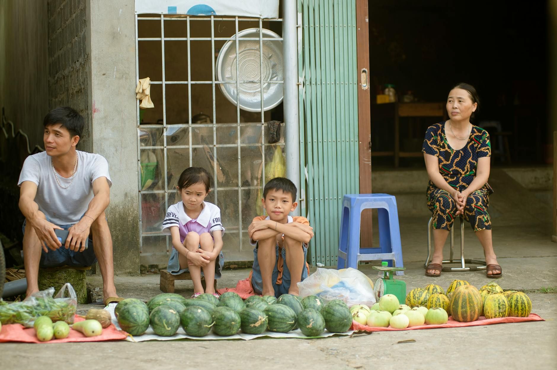 A family sits with fresh produce for sale in Hà Giang, Vietnam, capturing daily life.