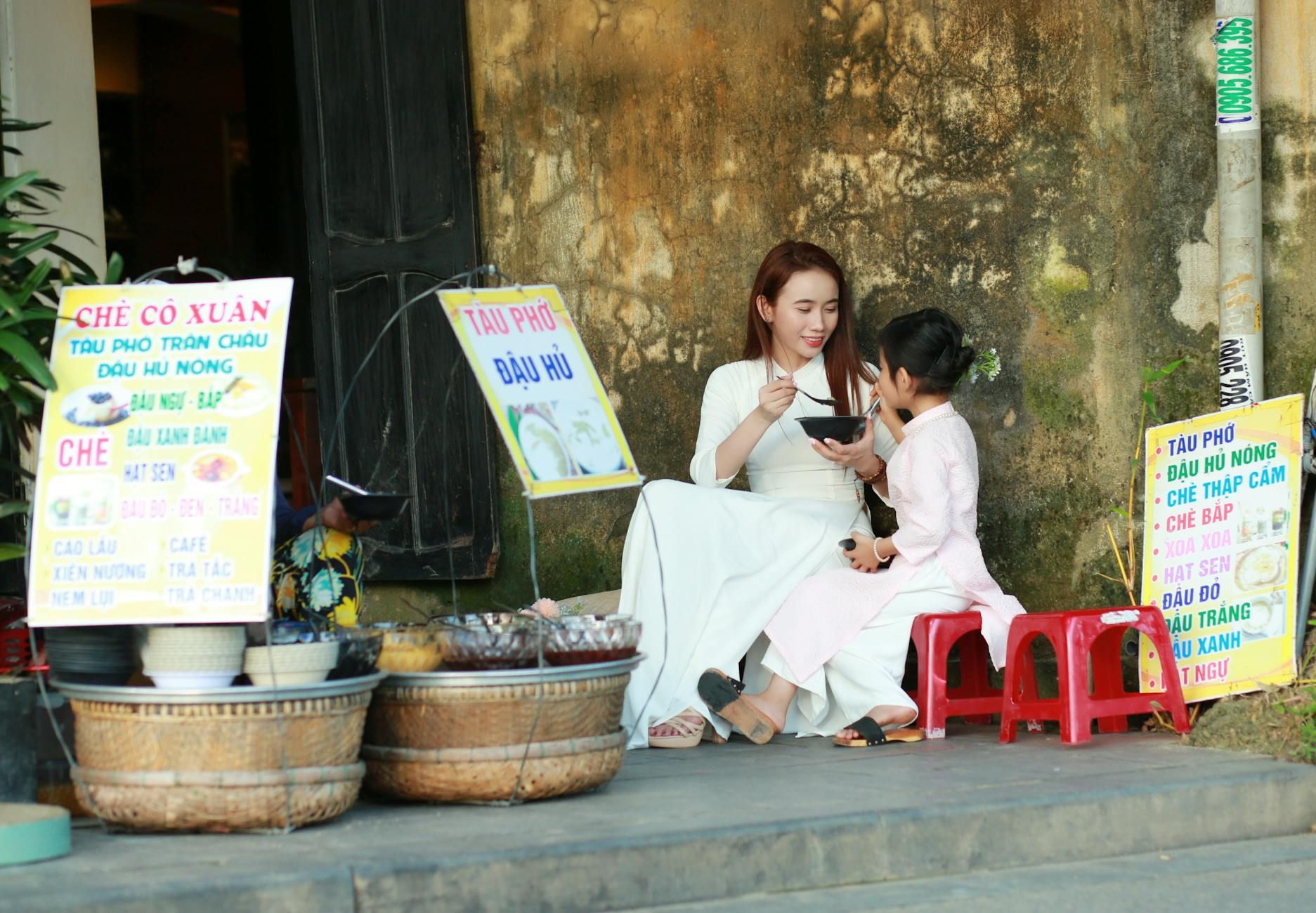 A woman and child enjoying a meal in Hội An, Vietnam, wearing traditional costumes.