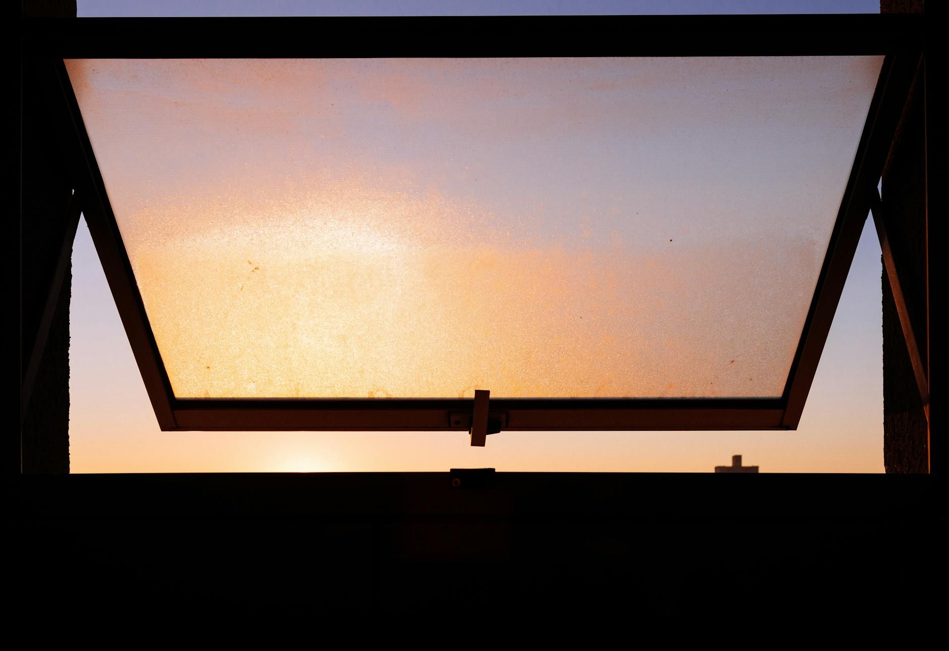 Warm sunlight filters through an open window at sunset, creating a serene atmosphere.