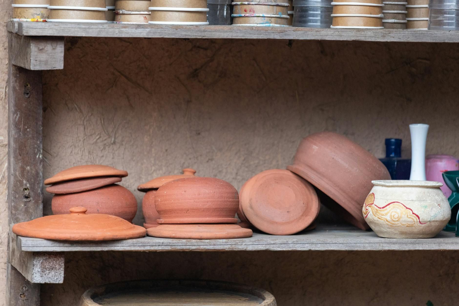 A collection of traditional clay pots on a rustic wooden shelf in Hà Nội, Việt Nam.