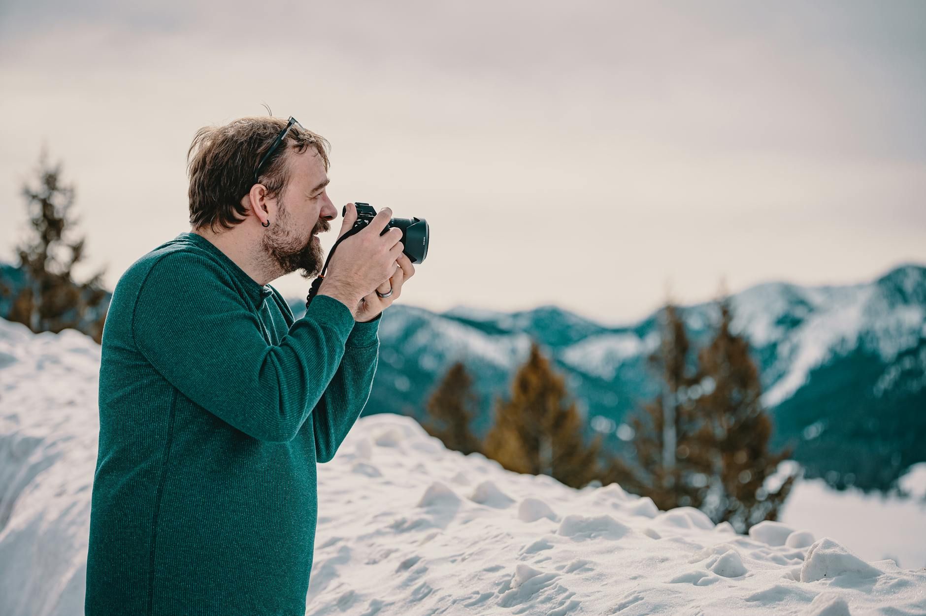 A photographer enjoys a snowy mountain view, capturing the serene winter landscape.