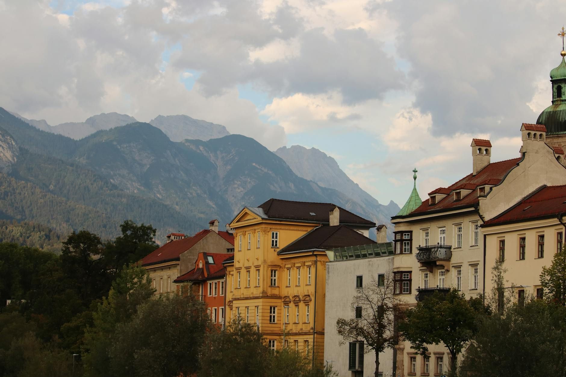 Charming Innsbruck buildings with mountainous backdrop under a cloudy sky.