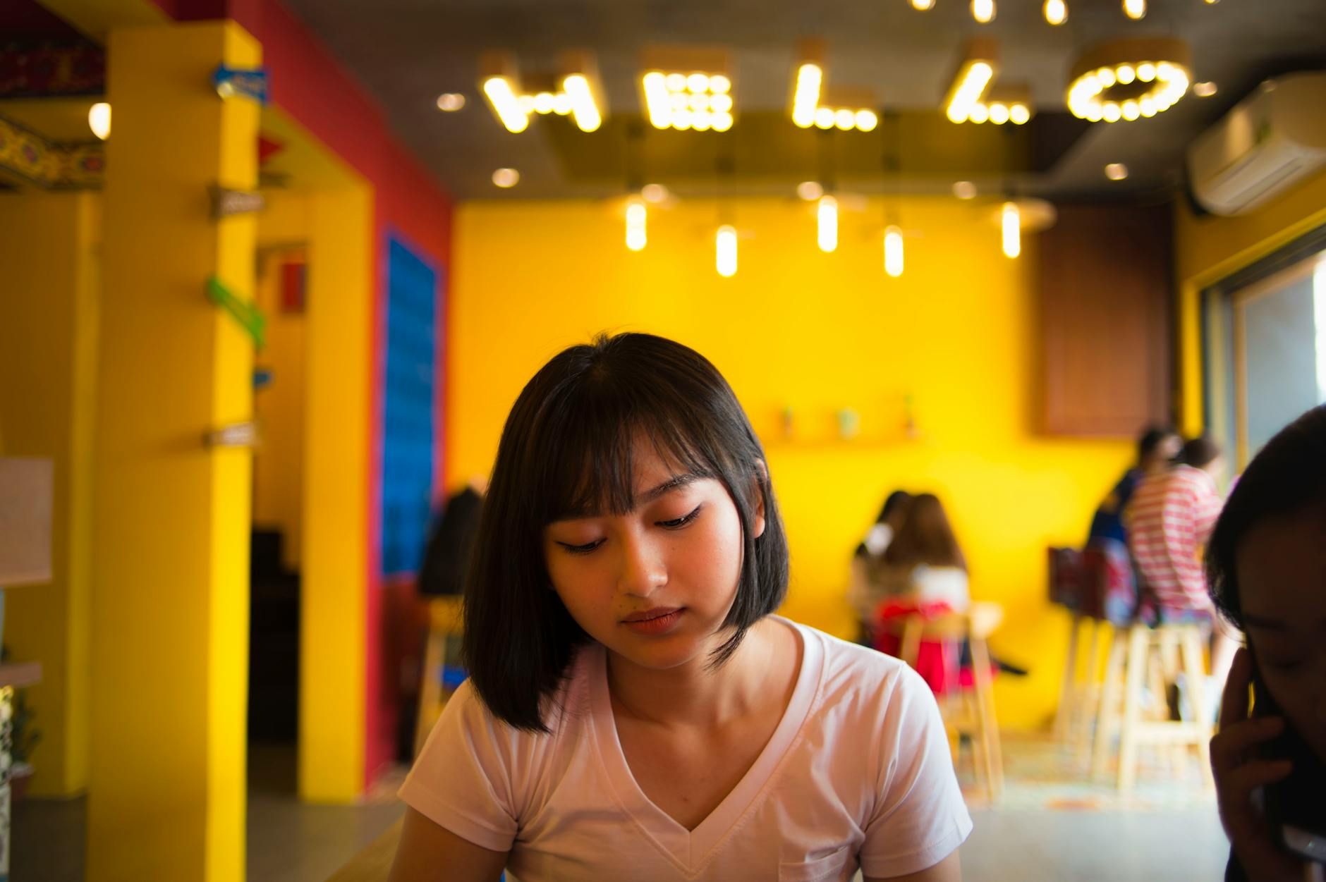 Asian girl seated in a colorful cafe with a warm ambiance in Vietnam.