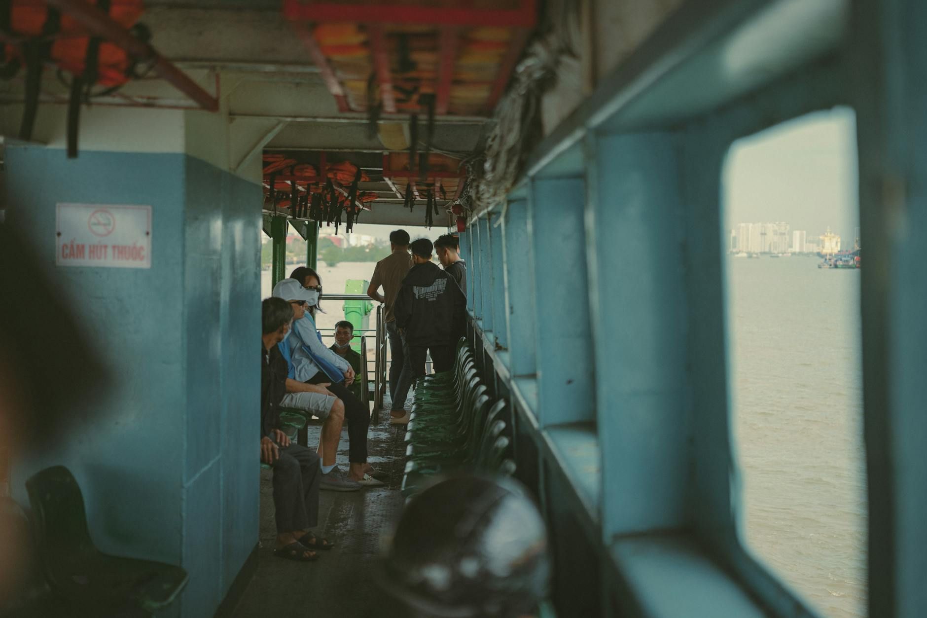 People onboard a ferry crossing the river in Ho Chi Minh City, capturing urban life in Vietnam.