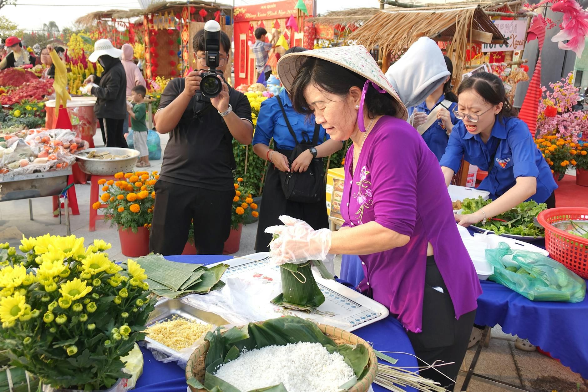 A bustling outdoor market with vendors preparing traditional foods amidst colorful flowers.
