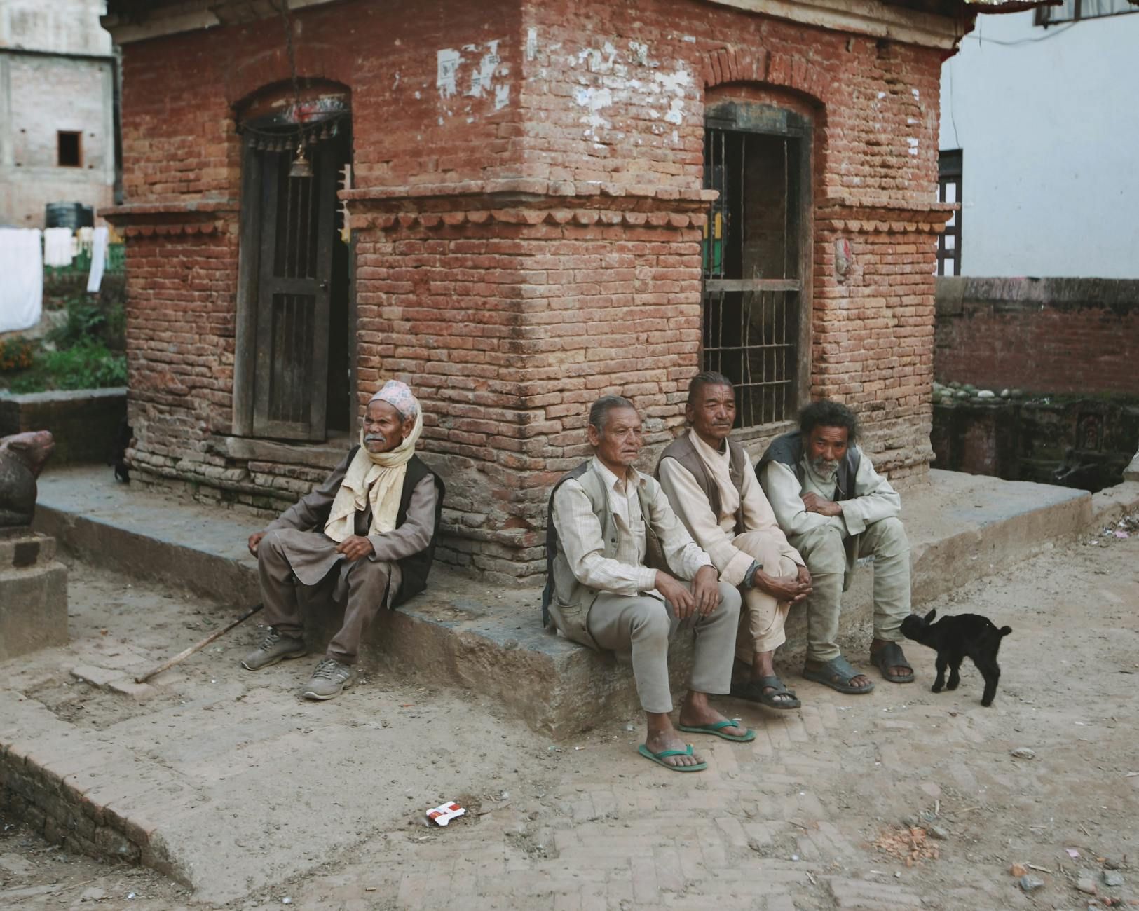 A group of elderly men sit outside a historic brick building, embodying community life.