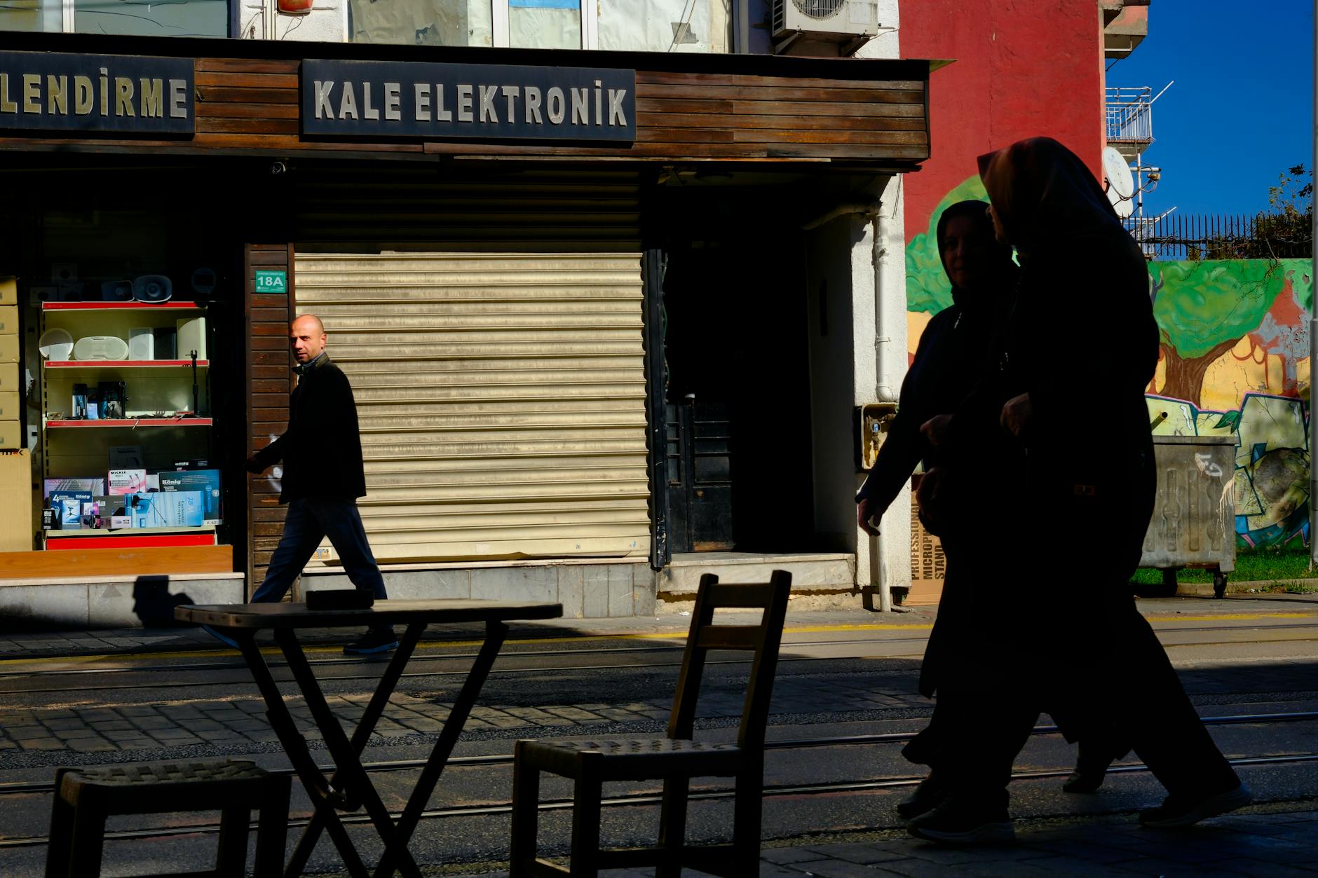 Silhouetted people walking by a shuttered shop in Bursa, Turkey.