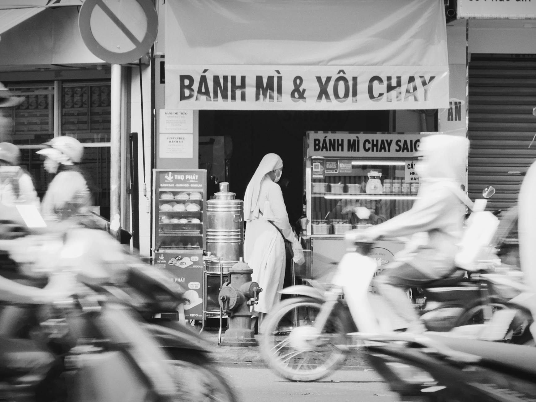 A bustling scene in Ho Chi Minh City featuring a bánh mì vendor surrounded by moving motorcycles.