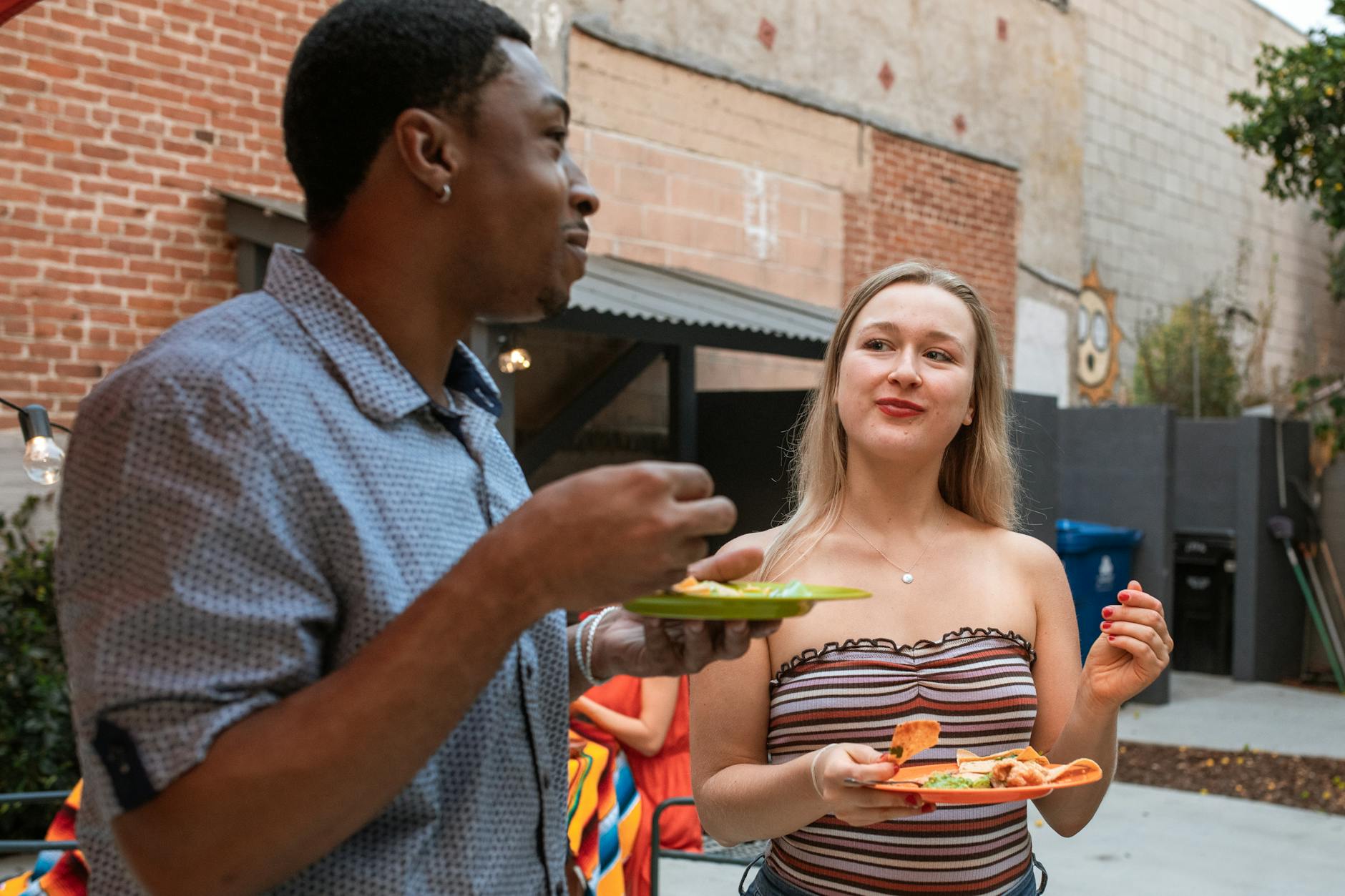 Two friends enjoying a casual meal outdoors, sharing laughter and food.