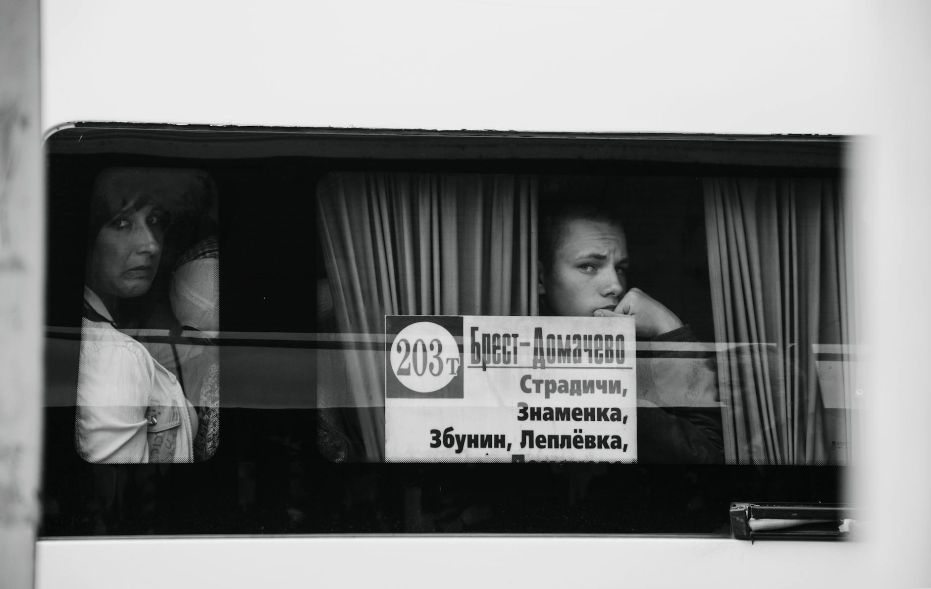 A black and white photo capturing thoughtful passengers gazing out a bus window.