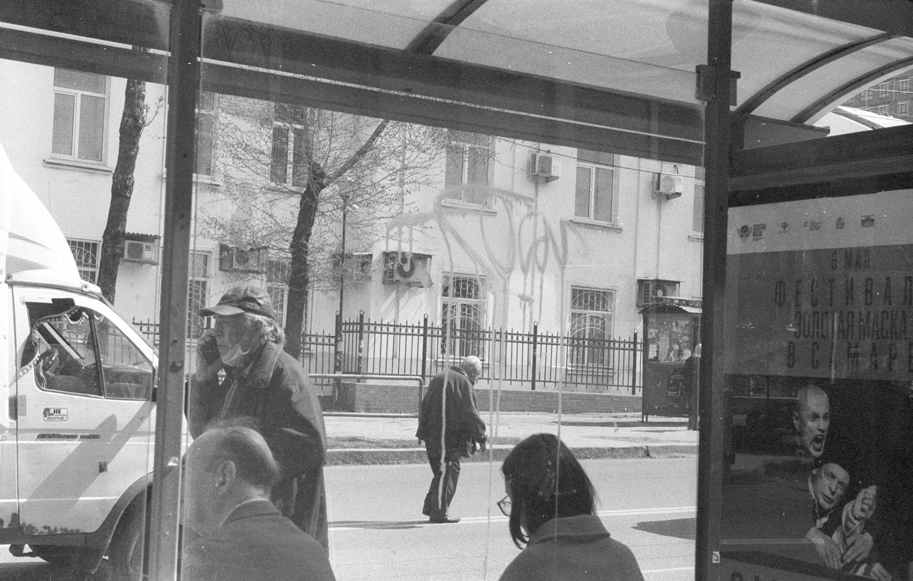 Monochrome urban scene depicting daily life at a bus stop with commuters.