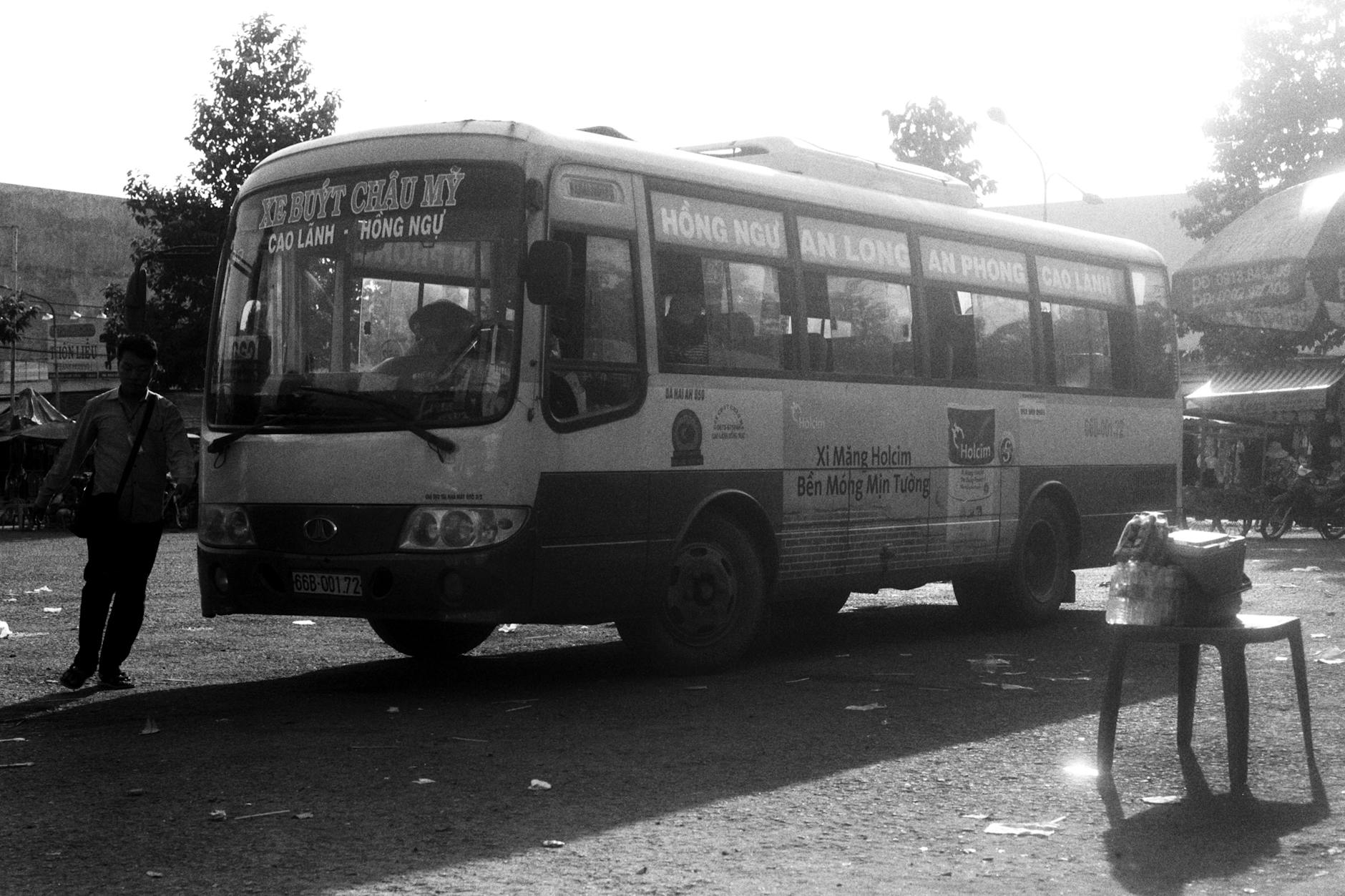 Black and white photo of a bus at a bustling street scene in Vietnam.