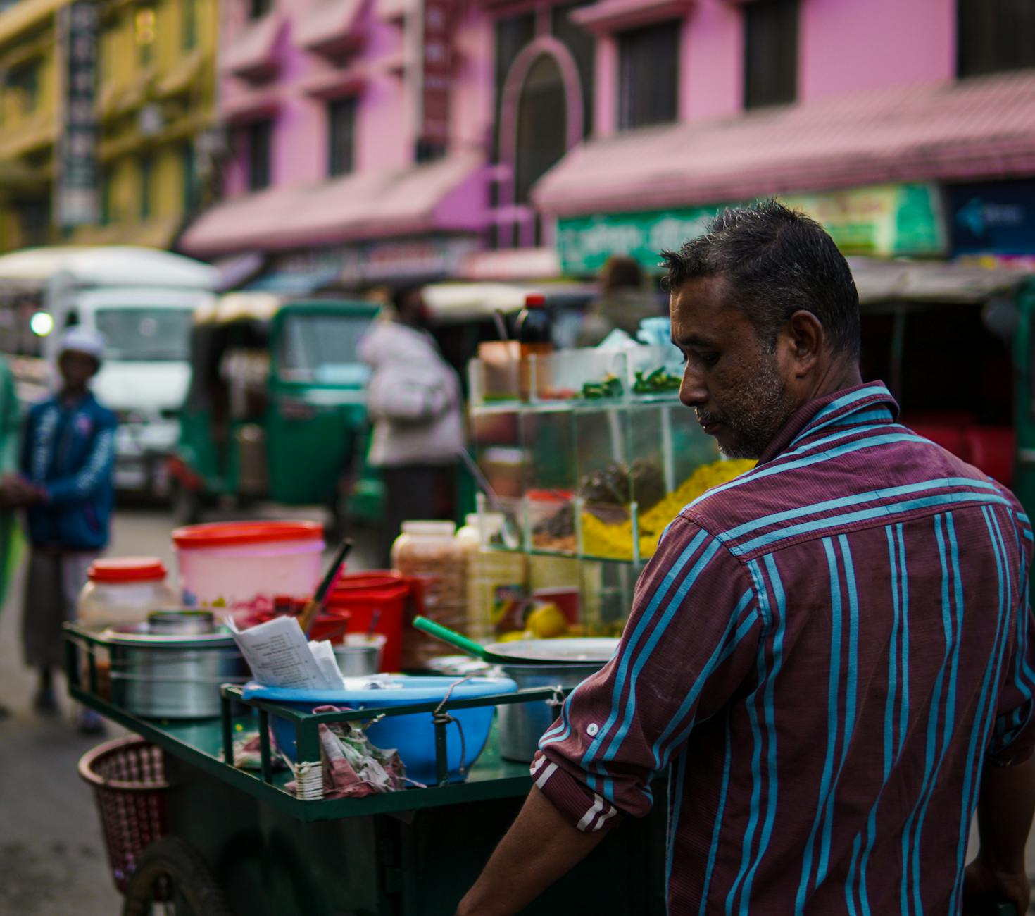A street vendor prepares traditional food in a bustling city setting, capturing lively urban culture.