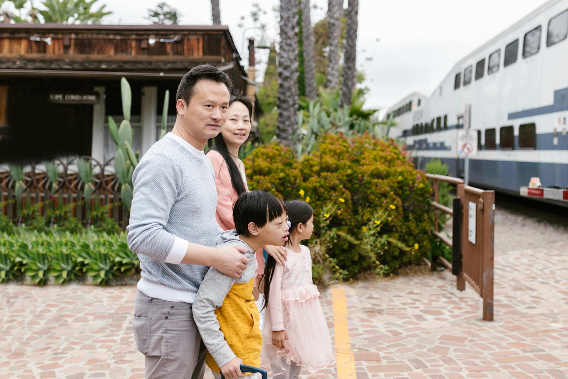 A family with children waits at a scenic train station, enjoying the outdoors together.