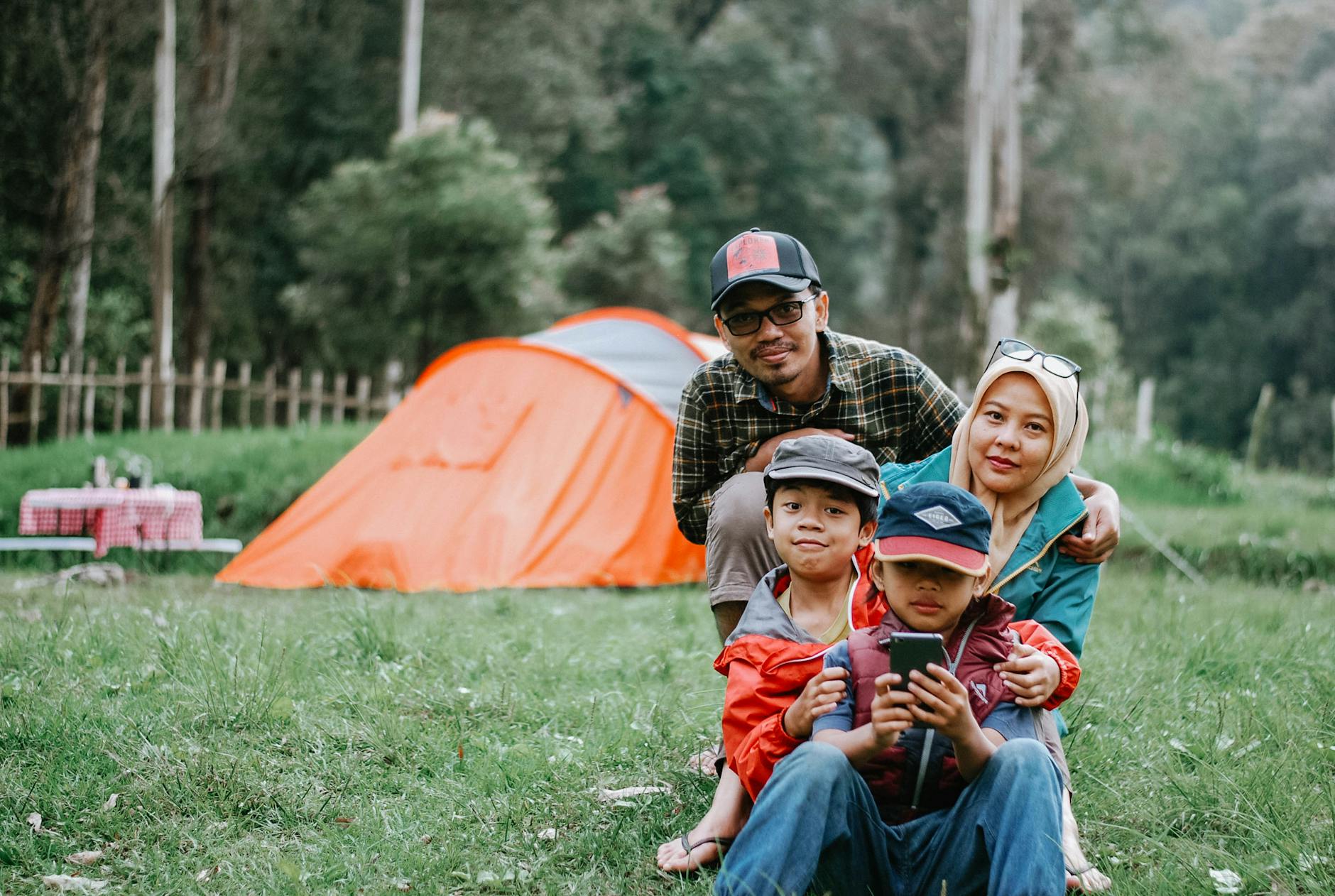 Happy family enjoying a relaxing camping trip in a lush forest setting, perfect for outdoor enthusiast inspiration.