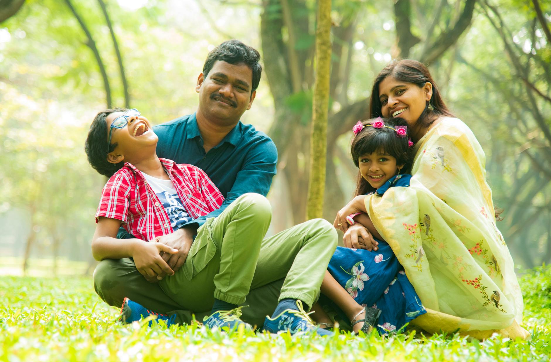 Cheerful family sitting on the grass, enjoying time outdoors together in a serene park.