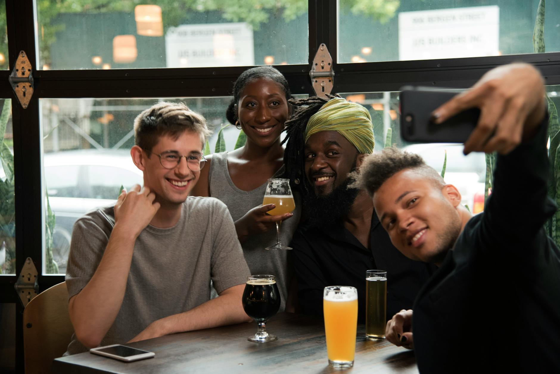 Group of cheerful friends taking a selfie, enjoying drinks at a bar.