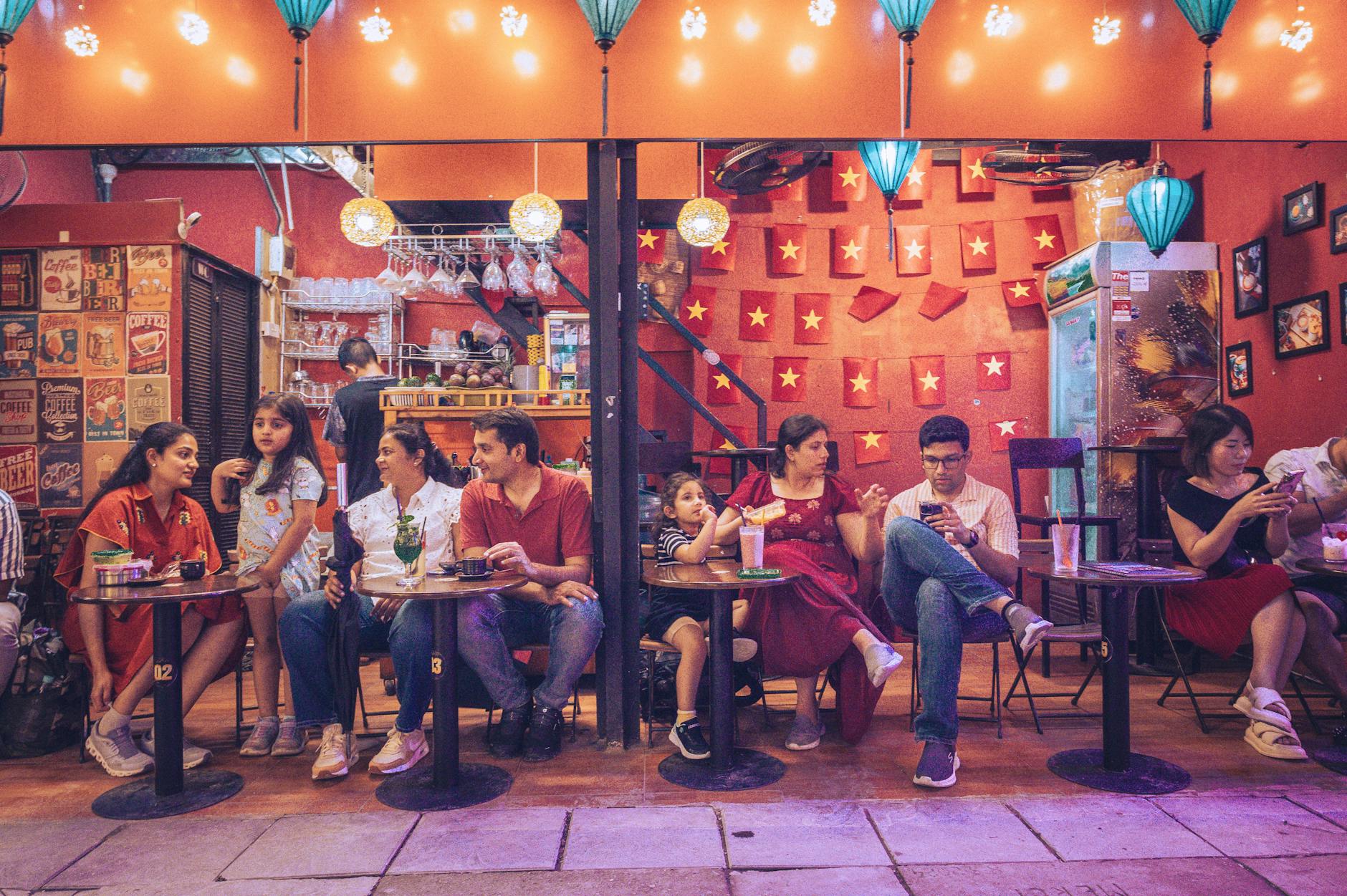 A lively evening at a street café with a diverse group enjoying conversations and drinks.