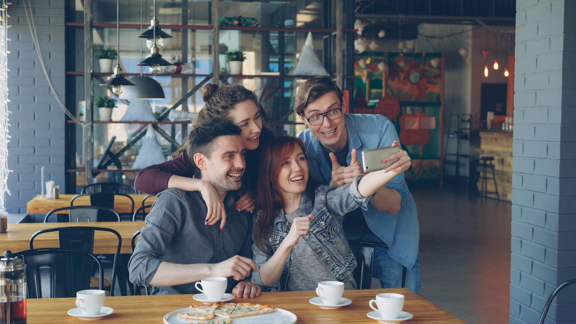 A joyful group of friends capturing a selfie together at a cozy café table.