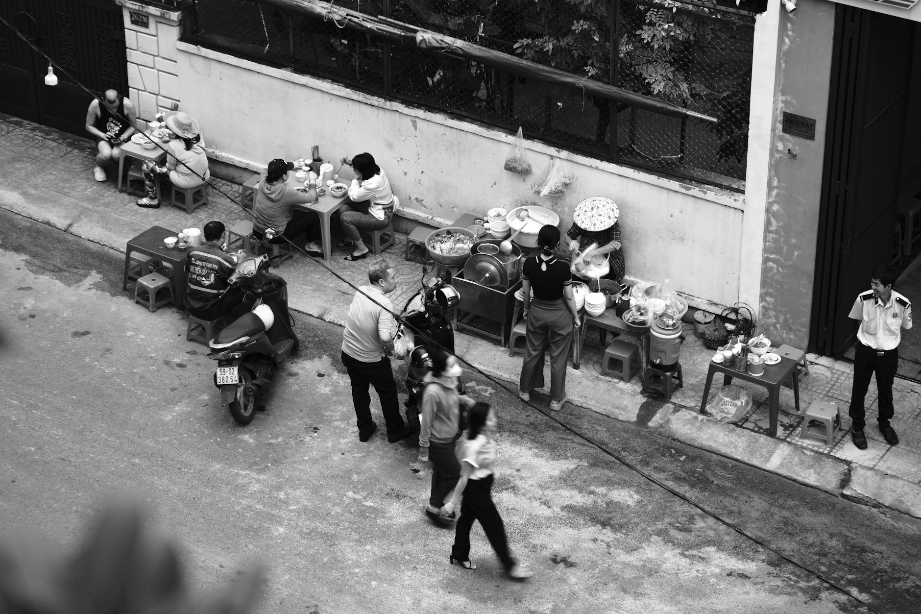Vibrant street food vendors and diners captured in a bustling Vietnamese street scene from above.