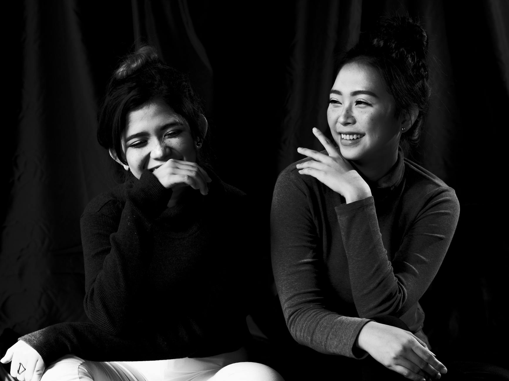 A candid black and white portrait of two women laughing together.