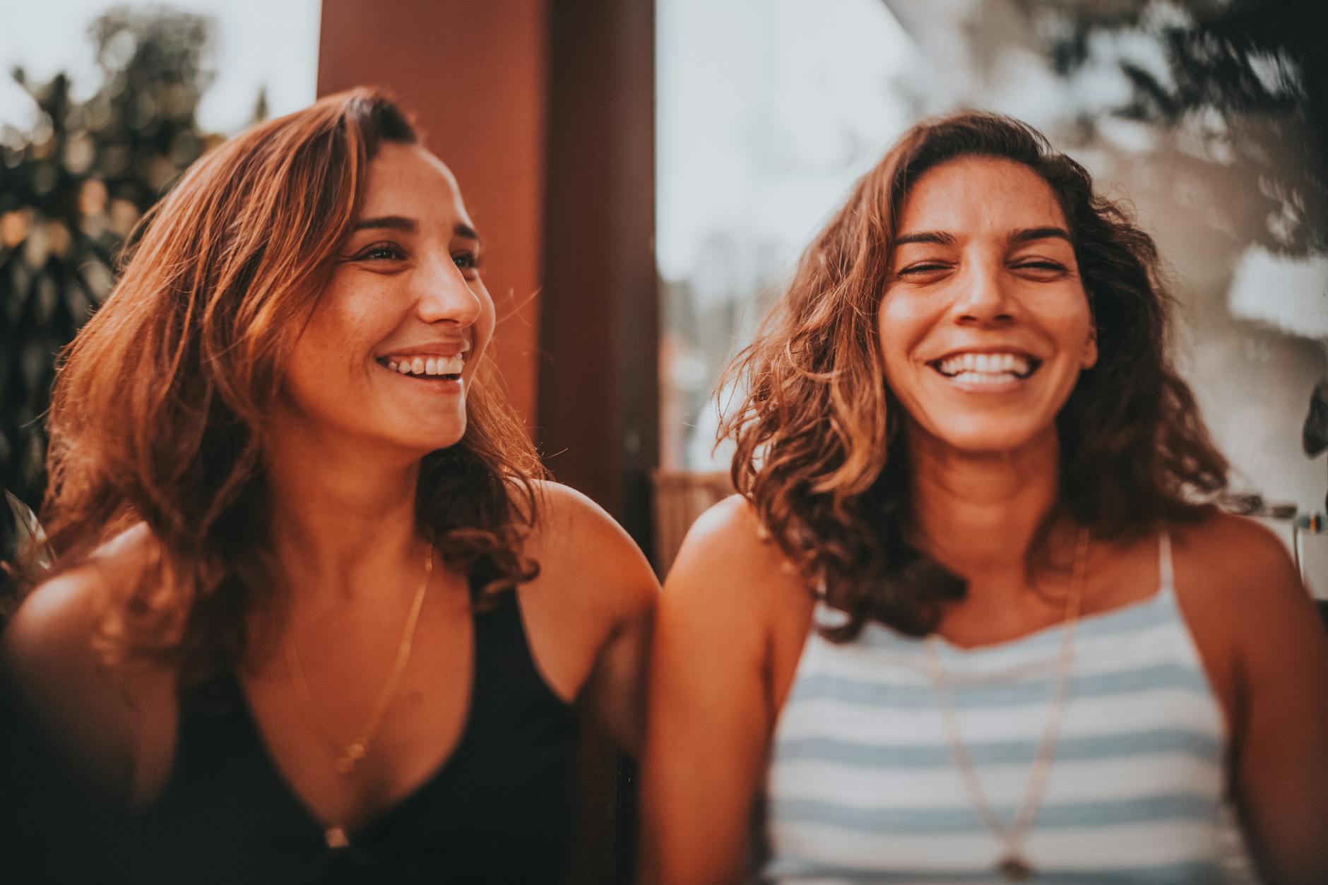 Two happy women sharing a laugh in an outdoor setting, exuding joy and friendship.
