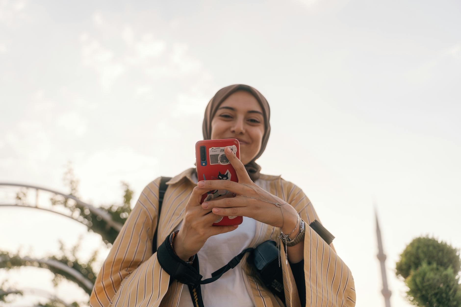 A joyful woman using her smartphone outside, captured in Konya, Türkiye.