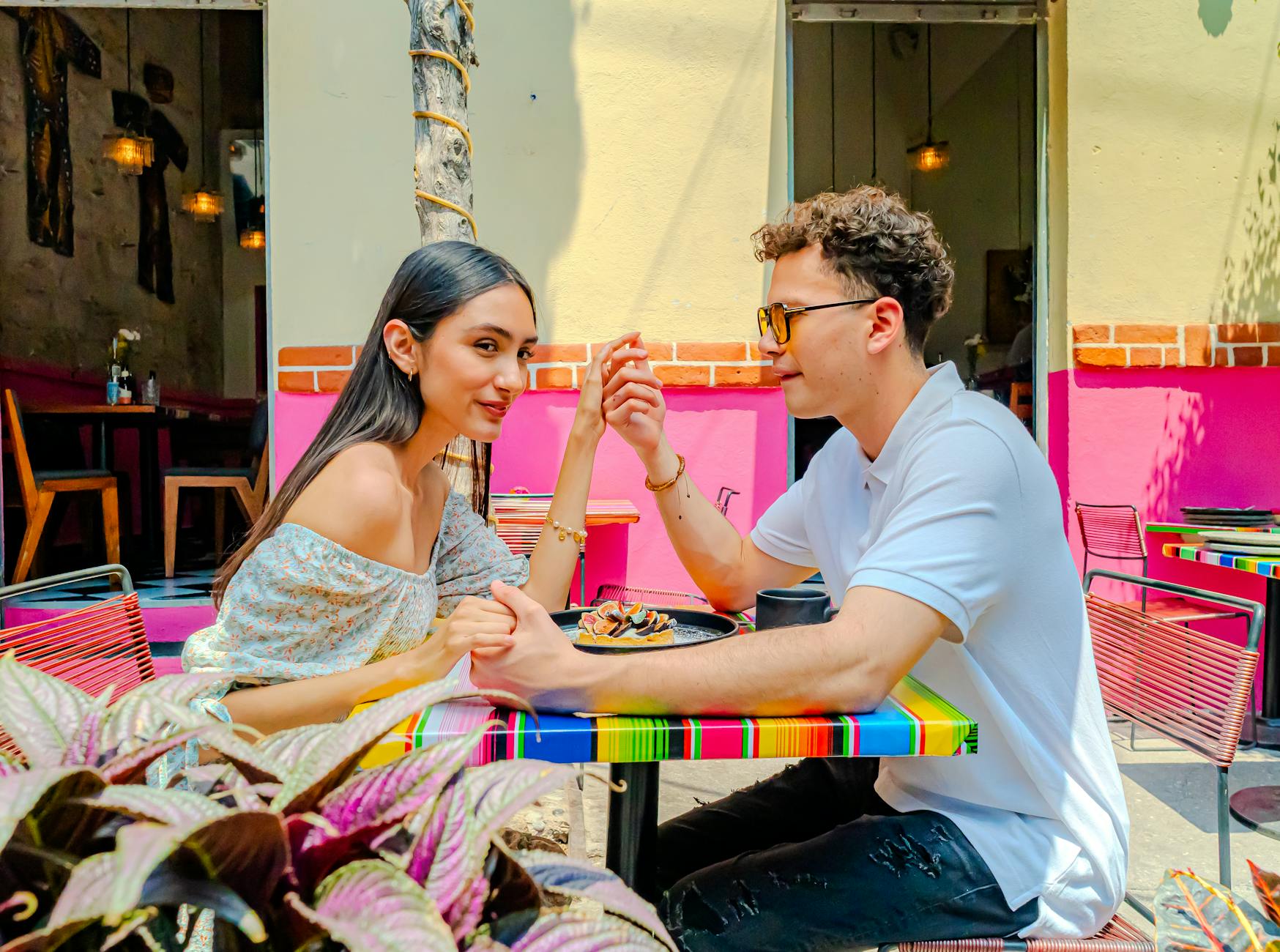 A young couple holding hands and enjoying a meal at an outdoor café in Ciudad de México.