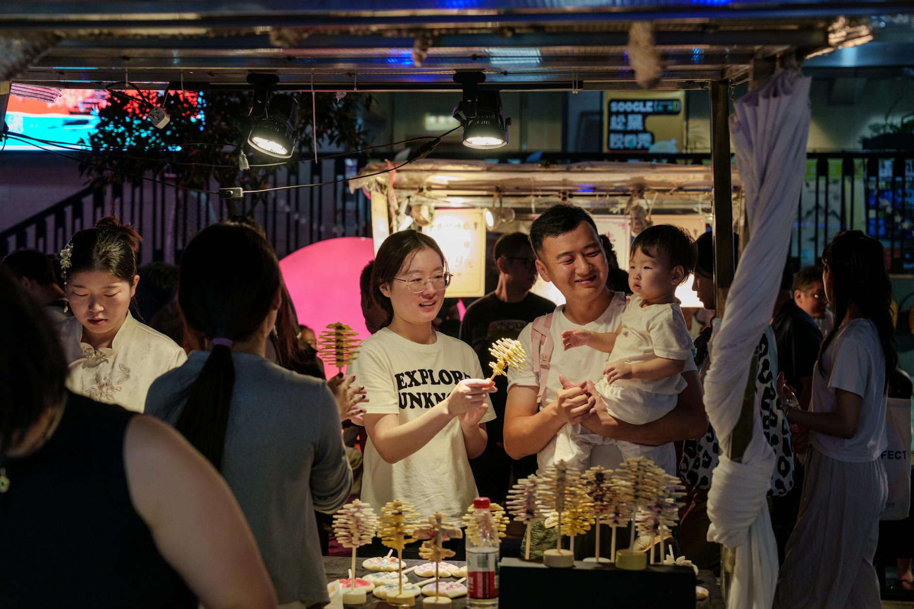 A family enjoys street food at a bustling night market scene.