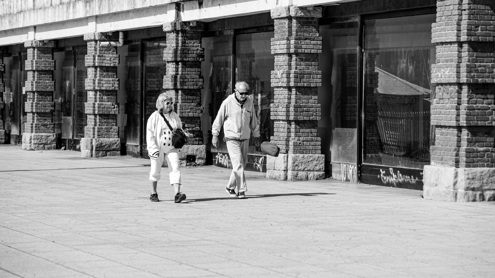 Monochrome photo of two senior adults walking in Mar del Plata, capturing urban life.