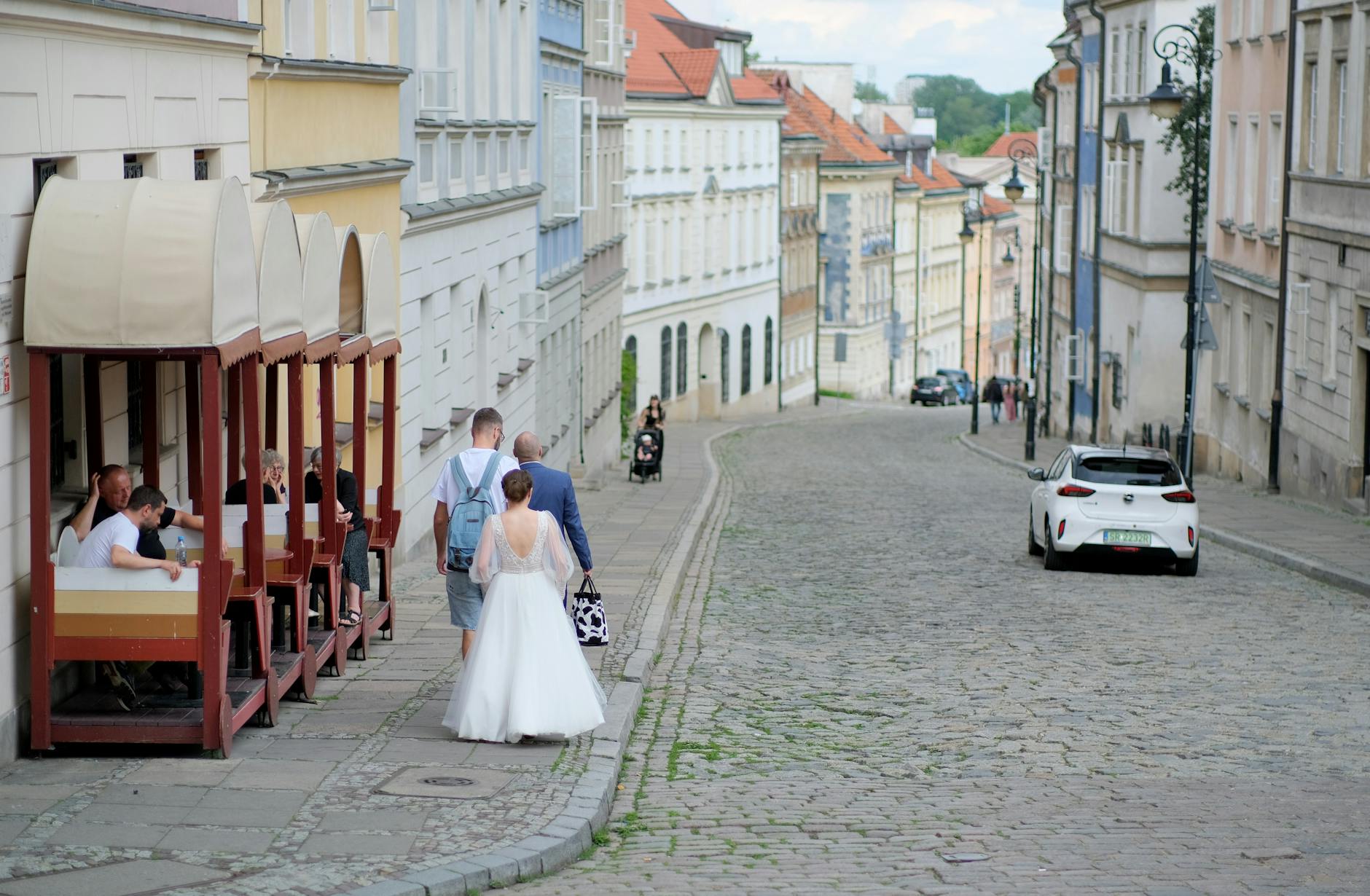 Couple walking down a European cobblestone street, surrounded by scenic architecture.