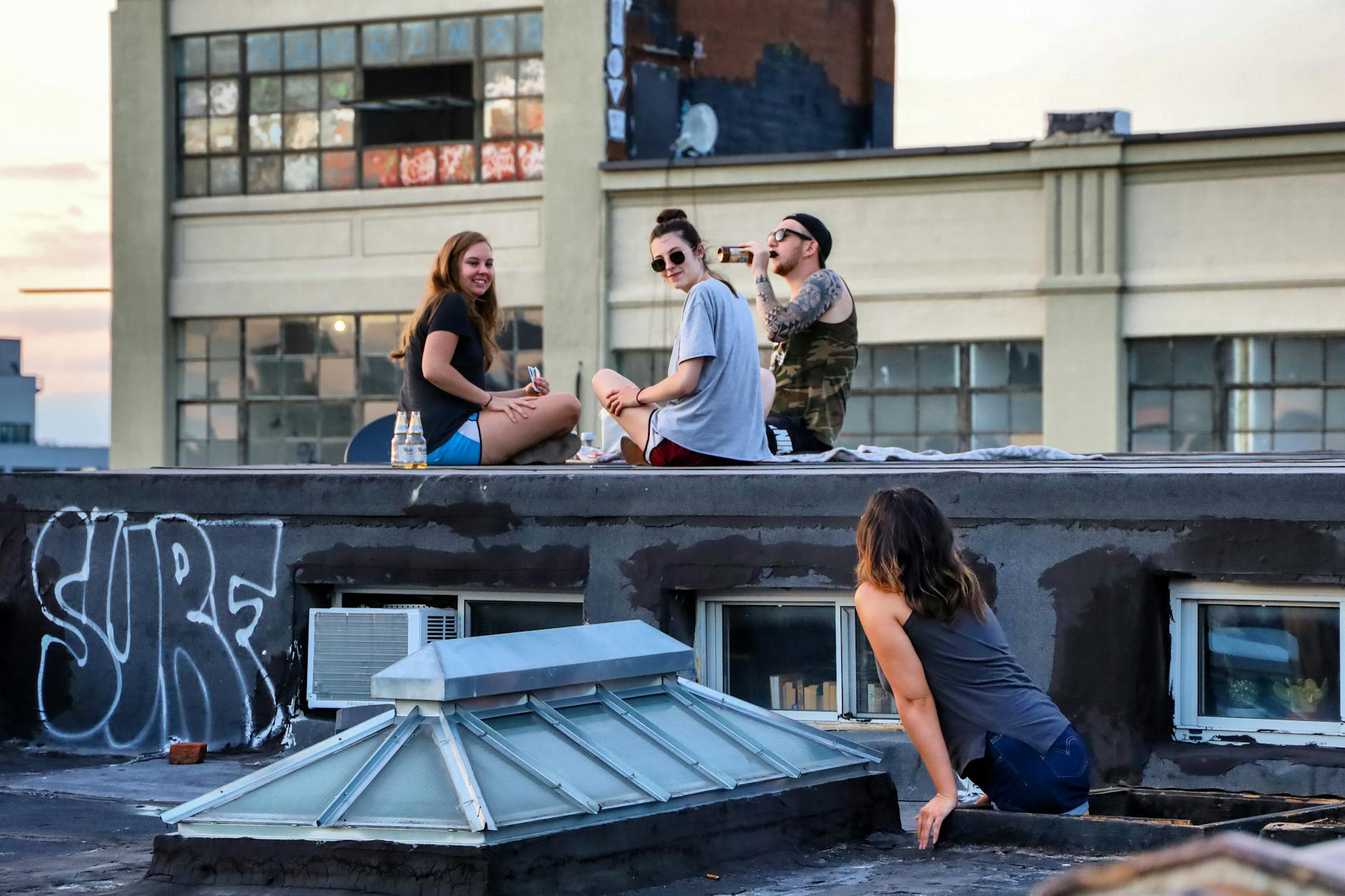 Group of friends relaxing on a New York rooftop during sunset. Urban vibe, graffiti, and chilled atmosphere.