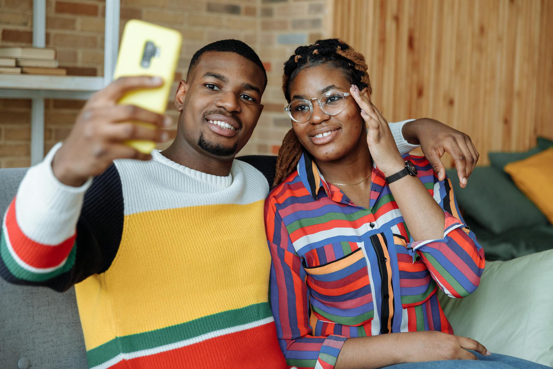 Happy couple takes a selfie in cozy indoor setting, smiling and enjoying the moment.