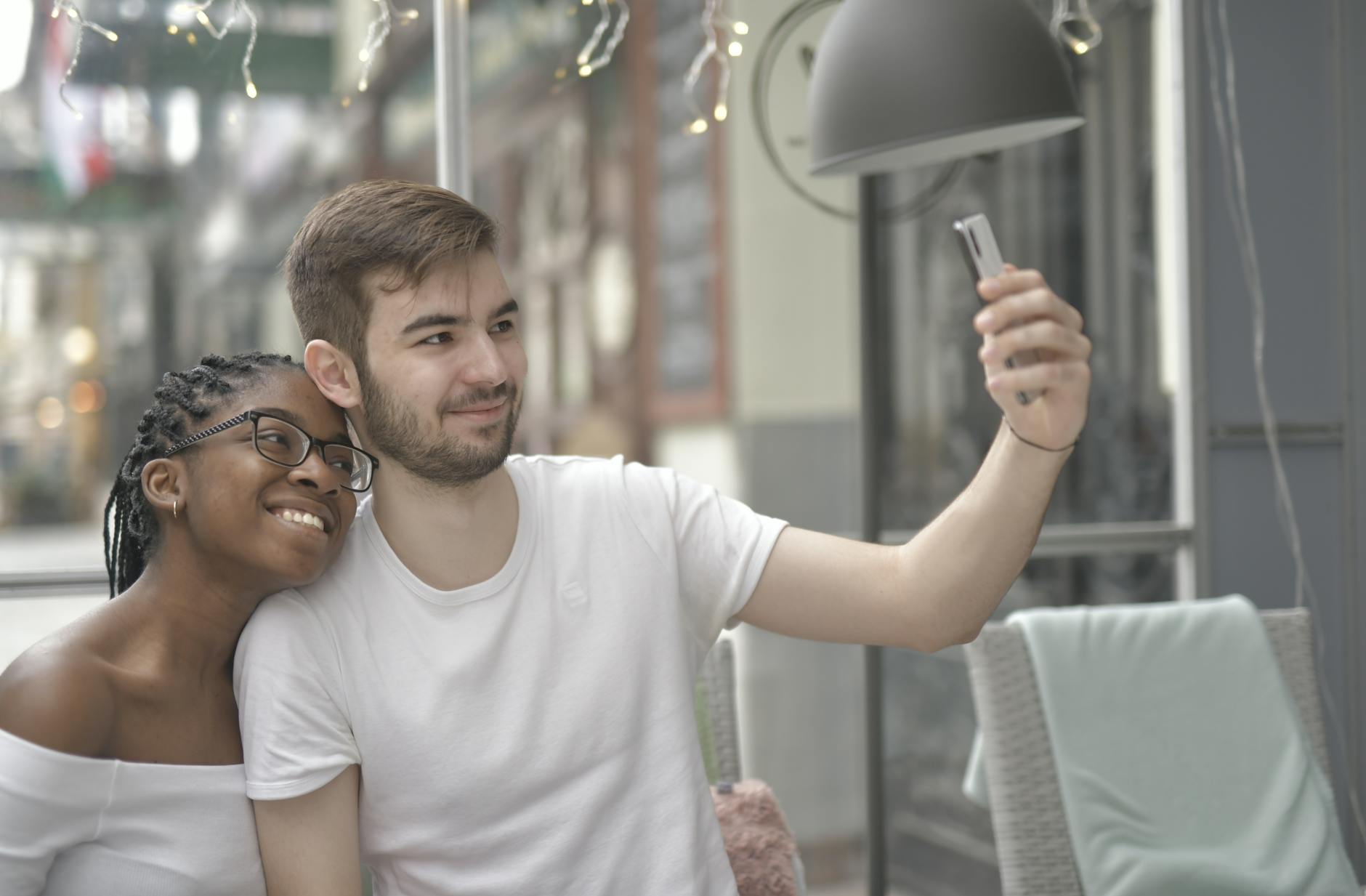 Young couple joyfully taking a selfie, capturing a moment of love and happiness in a casual outdoor setting.
