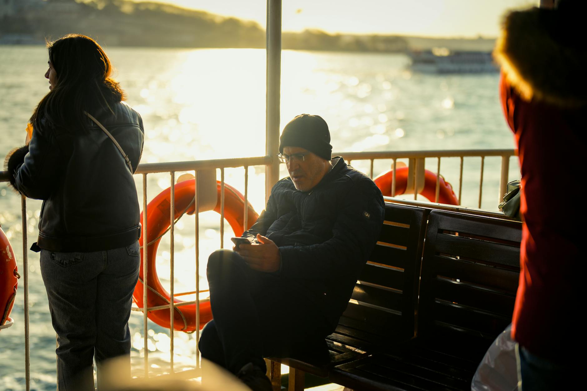 Passengers enjoying a ferry ride with warm sunlight reflecting on the water.