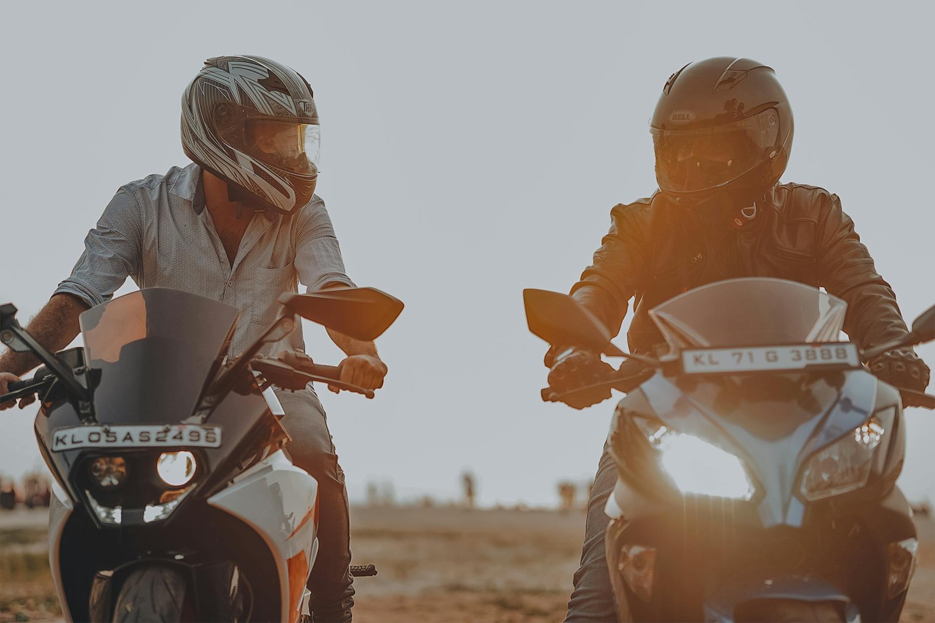 Two men riding motorcycles with helmets during sunset. Action and adventure concept outdoors.